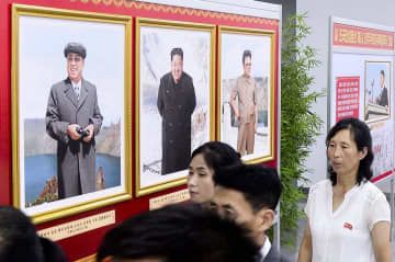 北朝鮮の建国75年を祝う写真展で展示された金正恩朝鮮労働党総書記の写真（中央）。左は故金日成主席、右は故金正日総書記の写真＝4日、平壌（共同）