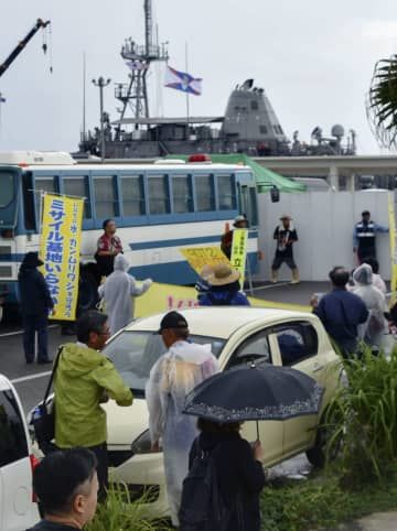 米海軍の掃海艦「パイオニア」（奥）の入港に反対し、石垣港周辺に集まった人たち＝7日午前、沖縄県・石垣島
