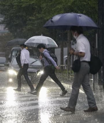 雨の中、通勤する人ら＝8日午前、JR東京駅前