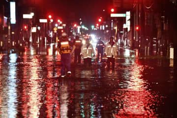台風13号の影響による大雨で冠水した福島県いわき市内の道路を歩く人たち＝9日未明