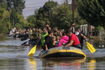 8日、ギリシャ中部の大雨で洪水に見舞われた地区からボートで避難する地元住民（ロイター＝共同）