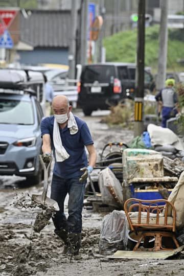 大雨から一夜明け、道路の泥を片付ける住民＝9日午前、福島県いわき市