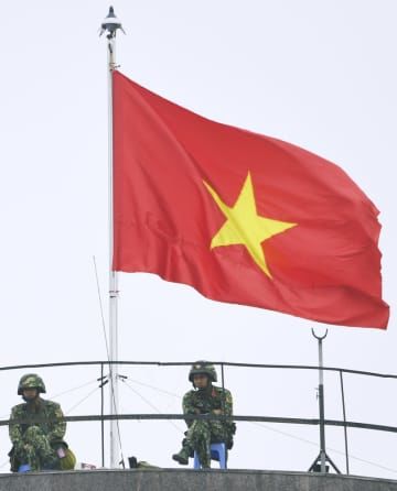 ハノイ市内で、ベトナム国旗が掲げられた建物の上で警備に当たる兵士＝2019年（共同）