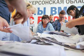 10日、ロシアが併合したウクライナ南部ヘルソン州で開票作業をする選挙管理委員会の担当者ら（タス＝共同）