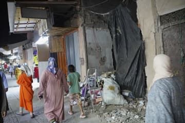 モロッコ・マラケシュ旧市街で、損壊した建物のそばを通り過ぎる人たち＝10日（共同）