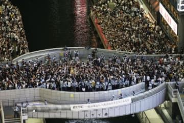 大阪・道頓堀に集まった人たち。戎橋の欄干には警察官が並んでいた＝14日午後8時51分