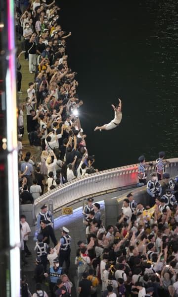 阪神がセ・リーグ優勝を決めた夜に、大阪・ミナミの道頓堀川の遊歩道から飛び込む人＝14日