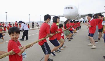 成田空港で開かれたイベントで、ジェット機を綱で引っ張る子どもたち＝17日午前