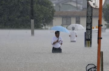 大雨の影響で冠水した道路を歩く人＝7月、福岡県久留米市