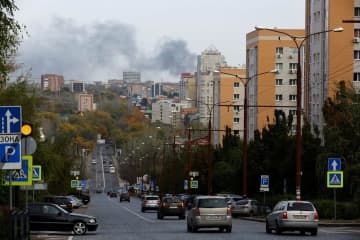 倉庫への爆撃で上がった煙が漂う市街地＝21日、ウクライナ東部ドネツク州（ロイター＝共同）