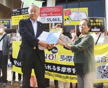 東京都多摩市の阿部裕行市長（左）に署名を手渡す市民団体の佐久間む津美共同代表＝27日午前、多摩市