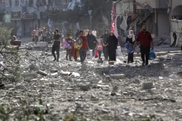 30日、イスラエル軍による攻撃後、自宅を離れるパレスチナ人たち＝パレスチナ自治区ガザ北部ガザ市（AP＝共同）