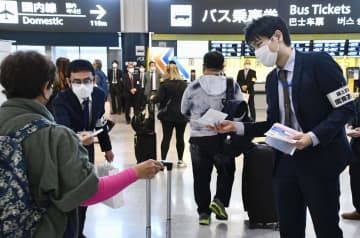 旅行客（左端）に「白タク」への注意を喚起するチラシを配る国交省の職員＝1日午前、成田空港