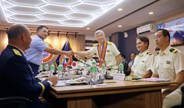 4日、マニラのフィリピン沿岸警備隊本部で握手するガバン長官（左から2人目）と海上保安庁の石井昌平長官（共同）