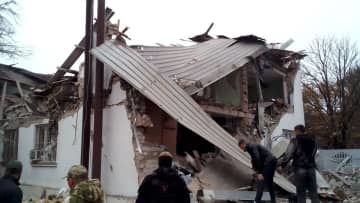 ロシアが実効支配するウクライナ南部ヘルソン州チャプリンカで、攻撃を受けた家屋を調べる人たち＝3日（タス＝共同）