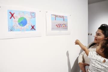 4日、米ロサンゼルスで、北朝鮮の子どもが描いた絵を鑑賞する親子（共同）