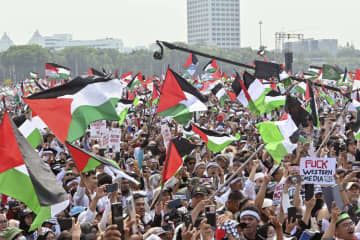 5日、ジャカルタの独立記念塔周辺で開かれた集会で、パレスチナの旗を掲げる人々（共同）