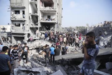 5日、パレスチナ自治区ガザ中部の難民キャンプで、イスラエル軍の攻撃があった現場を捜索する人たち（AP＝共同）
