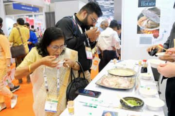 インドの首都ニューデリーで開かれた食品展示会で、日本産のホタテやハマチの刺し身を試食する人たち＝3日（NNA＝共同）
