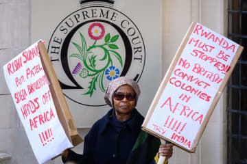15日、英ロンドンの最高裁前でプラカードを持って抗議をする人（ゲッティ＝共同）