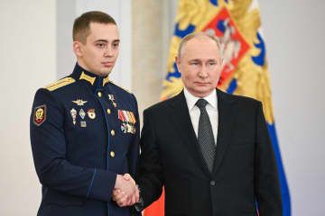 8日、モスクワのクレムリンで、ロシア軍将校（左）と握手するプーチン大統領（タス＝共同）