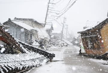地震で倒壊した建物に雪が降り積もる石川県珠洲市内＝13日午前