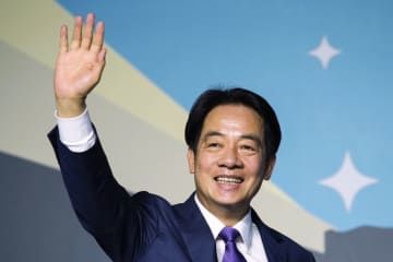 台湾総統選で勝利し、笑顔で手を振りながら記者会見に臨む民進党の頼清徳氏＝13日、台北（共同）