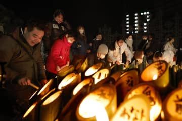 追悼会場で竹灯籠に火をともす人たち＝17日早朝、神戸市中央区の東遊園地
