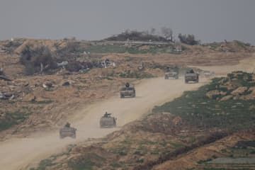 イスラエル南部から望んだガザ地区。境界付近をイスラエルの軍用車が走行している＝17日（AP＝共同）