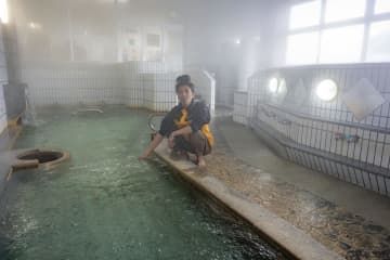 公衆浴場「海浜あみだ湯」の再開を前に湯を確かめる新谷健太さん＝19日午後、石川県珠洲市