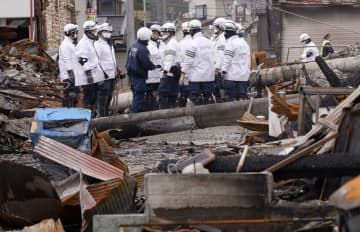 石川県輪島市の「輪島朝市」付近で行われた捜索活動で、全焼した家屋の前に集まる警察官ら＝19日午後