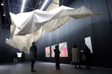 「札幌国際芸術祭」の会場で、気候変動を扱う作品を鑑賞する来場者ら＝20日午後、札幌市