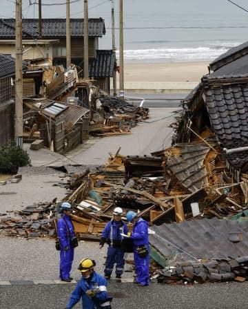 石川県輪島市門前町黒島町の地震で倒壊した家屋。電力復旧のため関係者が作業していた＝20日午後