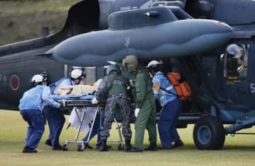 「武力攻撃予測事態」を想定した離島住民の避難訓練で、入院患者に見立てた人形を航空自衛隊のヘリコプターに運び込む人たち＝21日午前、鹿児島県屋久島町