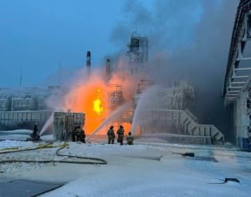 21日、ロシア・レニングラード州知事が通信アプリに投稿した、ウスチルガ港の燃料生産設備で消火作業を行う消防隊員の画像（ロイター＝共同）
