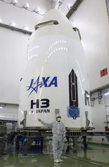 JAXAが公開した、H3ロケット2号機用の「フェアリング」。手前は岡田匡史プロジェクトマネジャー＝23日午後、鹿児島県の種子島宇宙センター