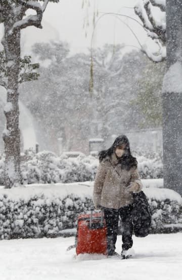 雪が降る中、JR鳥取駅前を歩く人＝24日午前8時32分