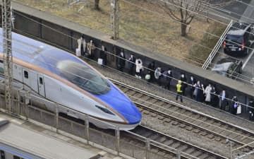 さいたま市中央区で停車した新幹線から降り、線路脇を歩く人たち＝23日