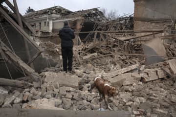 27日、ウクライナ・スラビャンスクで、ロシアの攻撃後、建物のがれきを見る住民（AP＝共同）