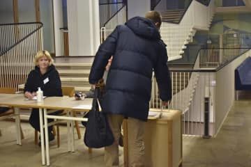 28日、フィンランド大統領選で投票する有権者（右）＝ヘルシンキ（共同）