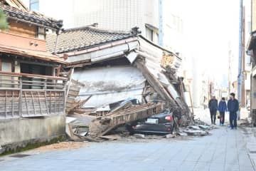 地震により崩れた洋服店と下敷きになった車＝2日、石川県七尾市の「一本杉通り」