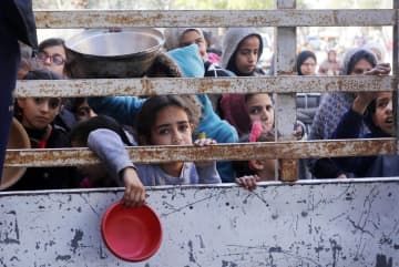 28日、パレスチナ自治区ガザ中部デールバラハで食料の配給を待つ子どもら（ゲッティ＝共同）