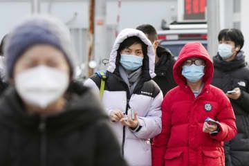マスクを着けて北京市内を歩く人たち＝31日（共同）