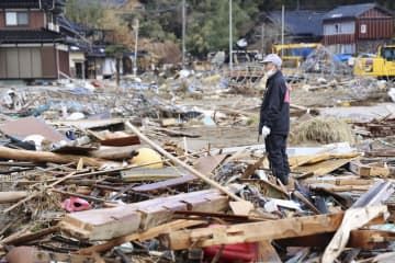 被災した自宅の周辺で、がれきの中から捜し物をする堀浜浩さん＝31日午前、石川県能登町の白丸地区