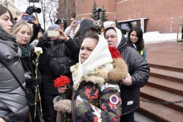 3日、モスクワ・クレムリン脇の「無名戦士の墓」前で花束を手にするマリヤ・アンドレーエワさん（中央）ら（共同）