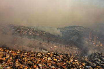 3日、チリ中部バルパライソ郊外で煙に包まれる市街地（ゲッティ＝共同）