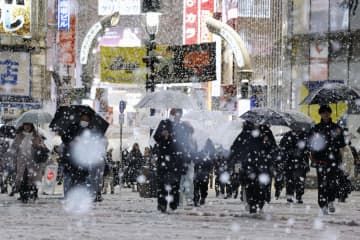 雪が降る東京・渋谷のスクランブル交差点を歩く人たち＝5日夜