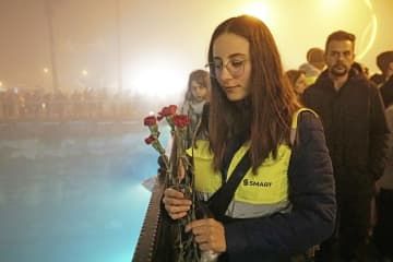 トルコ・シリア大地震の追悼式で、被災地を流れる川に花を投げる女性＝6日、トルコ南部アンタキヤ（共同）