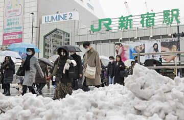 雪が残るJR新宿駅前を歩く人たち＝6日午前