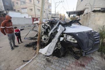 7日、パレスチナ自治区ガザ南部ラファで、イスラエル軍の攻撃により壊れた車を見る人＝7日（ロイター＝共同）